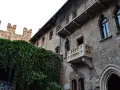 A historic brick building with ivy-covered walls and Juliet's balcony in Verona, Italy.