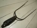 A rusty, old pitchfork with three tines lies on a white wooden floor.