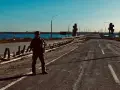 Soldat på en förstörd bro över en flod. Scenen är en absurd synonym för krigets fasor.