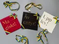 Grattis! Kort med texten "Magiskt!", "Äventyr!" och "Upplev!" i guldfärgad skrivstil, dekorerade med blågula band.