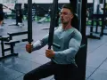 Man tränar bröstmusklerna på ett gym. Han använder en maskin för att hårddra sina muskler och bygga styrka.