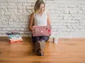 Kvinna med rosa laptop och böcker, redo att skriva. En polemik synonym kan vara debatt eller diskussion.