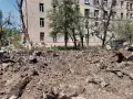 Enormt jordhög framför en tegelbyggnad, med trasiga träd och rester av en kollapsad struktur. En påminnelse om tumult.