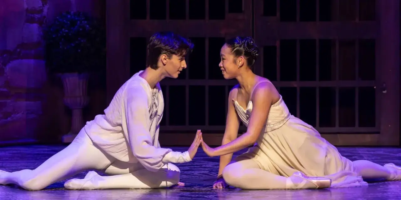 Romeo och Julia handling: Två dansare i balettkläder, en man i vitt och en kvinna i ljusgult, möts på scenen med händerna mot varandra.