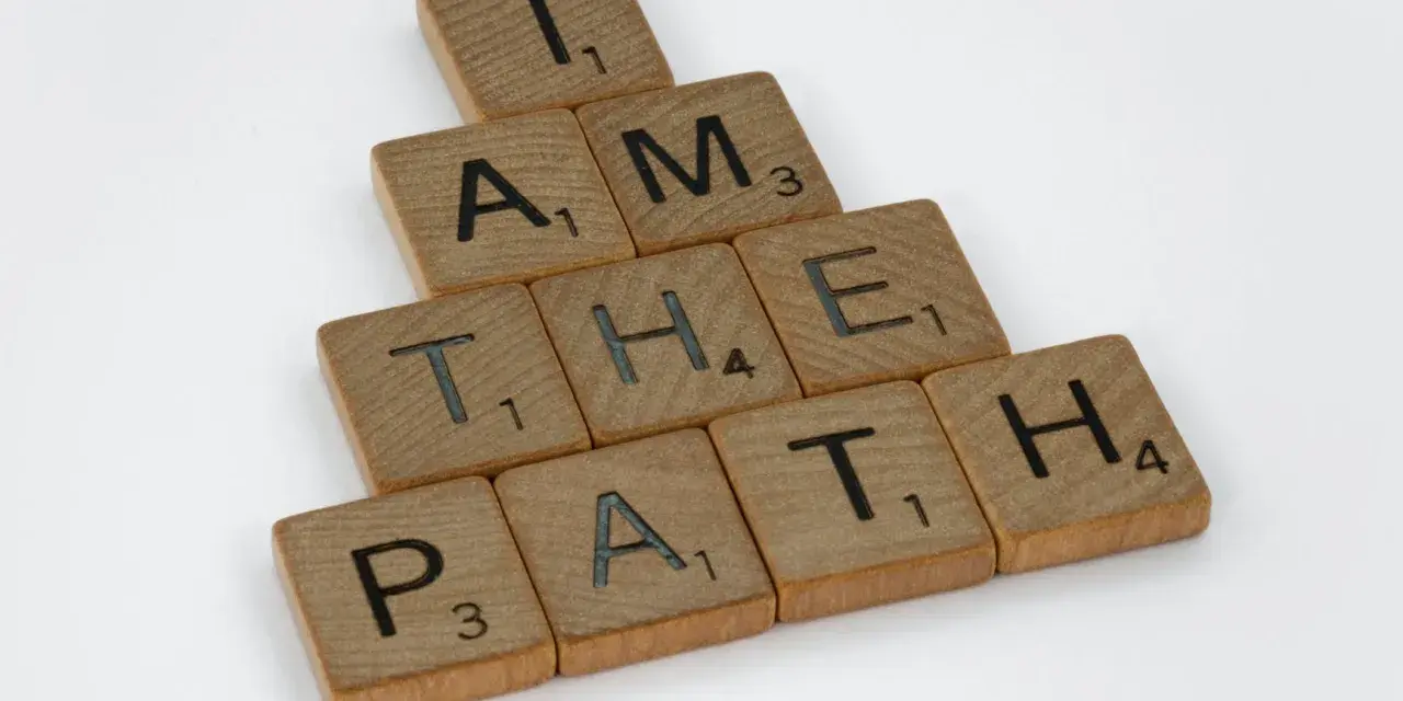 Bokstäver på träbrickor bildar frasen "I AM THE PATH" i en bunden form.