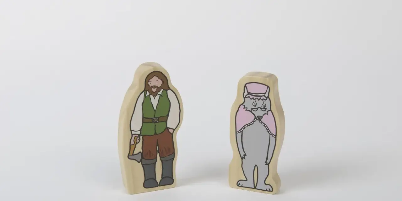 Två träfigurer: en man med yxa, klädd som en skogshuggare, och en varg i hatt och cape. Kanske redo för ett äventyr med tjuvar och banditer.