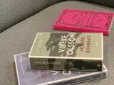 Tre böcker ligger på en soffa. En av dem heter "Molnfri bombnatt" av Vibeke Olsson.