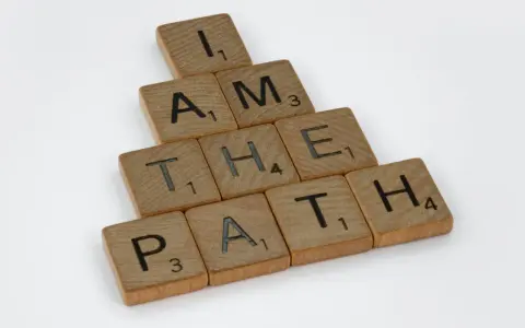 Bokstäver på träbrickor bildar frasen "I AM THE PATH" i en bunden form.