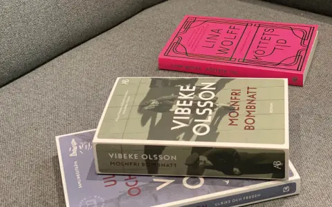 Tre böcker ligger på en soffa. En av dem heter "Molnfri bombnatt" av Vibeke Olsson.