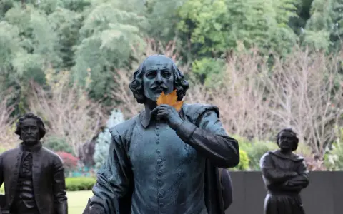Staty av Shakespeare med ett löv framför munnen, som ett sonett exempel. Bakom syns andra statyer och träd.