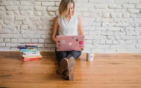 Kvinna med rosa laptop och böcker, redo att skriva. En polemik synonym kan vara debatt eller diskussion.