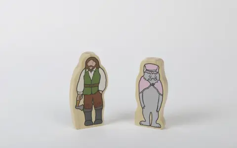 Två träfigurer: en man med yxa, klädd som en skogshuggare, och en varg i hatt och cape. Kanske redo för ett äventyr med tjuvar och banditer.
