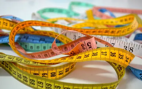 Många färgglada måttband ligger huller om buller. Ett gult måttband med siffror som 67, 68, 69, 70, 71, 72, 73, 74 ger ny rad.