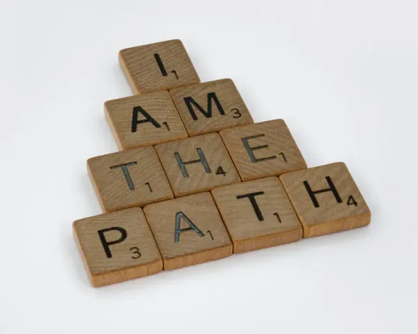 Bokstäver på träbrickor bildar frasen "I AM THE PATH" i en bunden form.