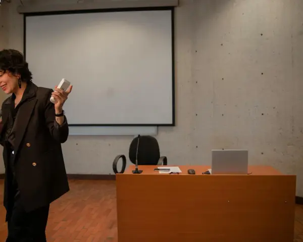 En kvinna håller mikrofon och en fjärrkontroll, redo att presentera en tes.