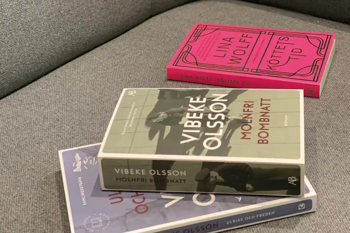 Tre böcker ligger på en soffa. En av dem heter "Molnfri bombnatt" av Vibeke Olsson.