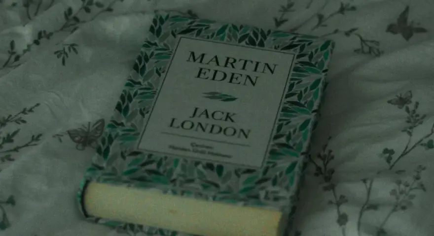 En bok med titeln "Martin Eden" av Jack London ligger på ett mönstrat tyg. En perfekt bok för att förlora sig i en novell.