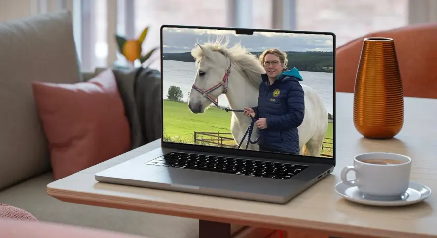 En kvinna med glasögon och en blå jacka håller i en vit häst på en laptop. Bilden visar vad referat betyder: en sammanfattning av en händelse.