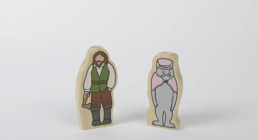 Två träfigurer: en man med yxa, klädd som en skogshuggare, och en varg i hatt och cape. Kanske redo för ett äventyr med tjuvar och banditer.
