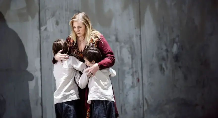 Medea, med en blick av sorg, kramar sina barn. En scen ur en pjäs om Jason och Medea.