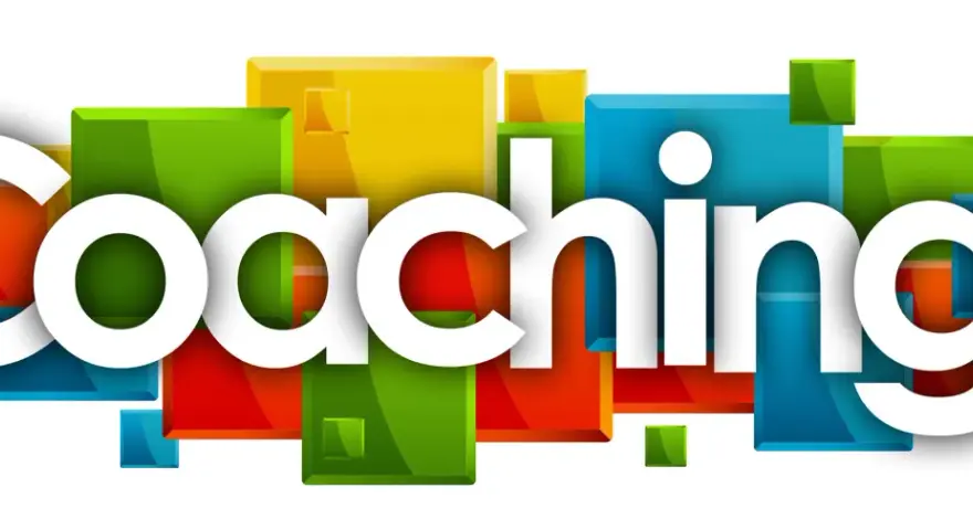 Stora vita bokstäver bildar ordet "Coaching!" framför en bakgrund av färgglada, glänsande kuber. Det här är vad coach betyder.