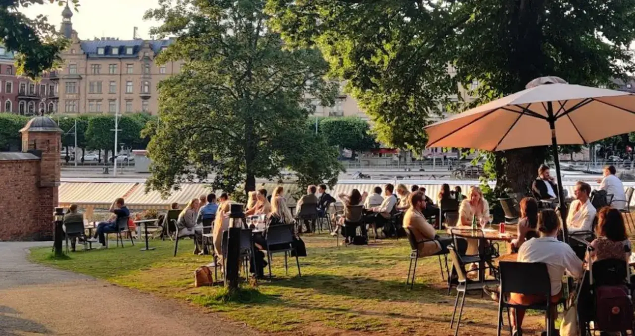 Människor njuter av en solig dag på en uteservering vid vattnet. En perfekt synonym för en trevlig krog.