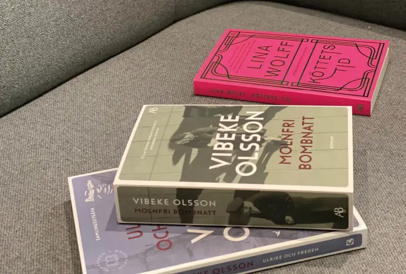 Tre böcker ligger på en soffa. En av dem heter "Molnfri bombnatt" av Vibeke Olsson.